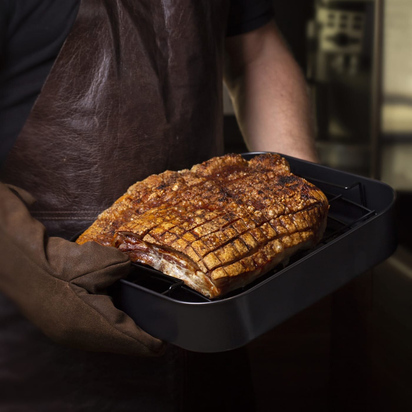 Mann holder ildfast form med stekt ribbe