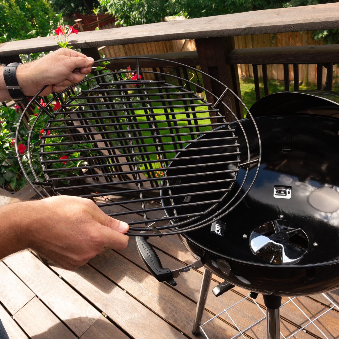 Mann holder opp grillrist over kullgrill