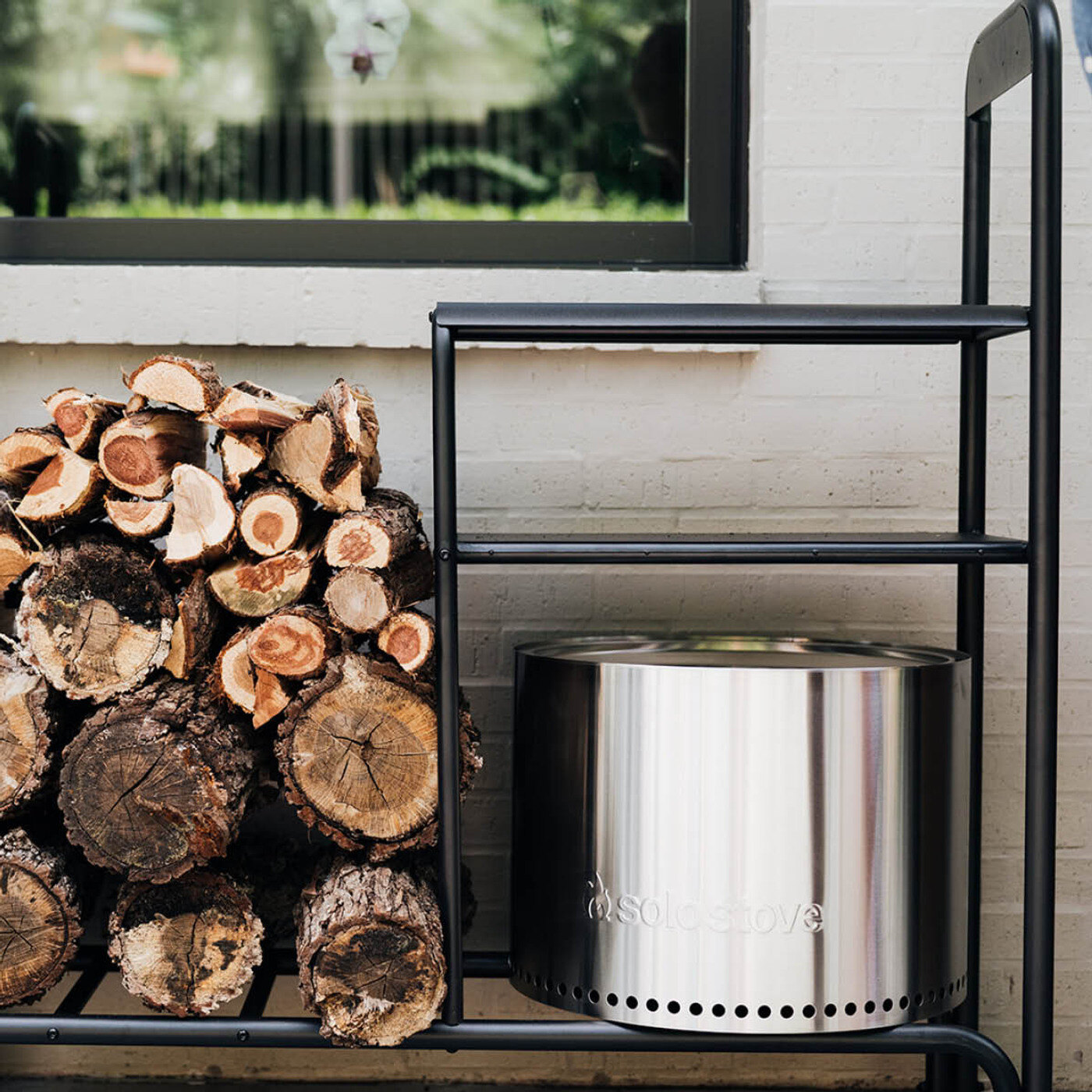 Solo Stove b&aring;lpanne p&aring; stativ ved en vedstabel