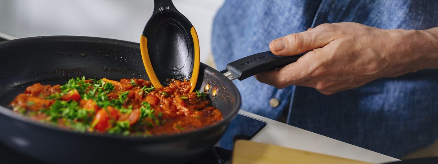 En person steker grønnsaker i en stekepanne.