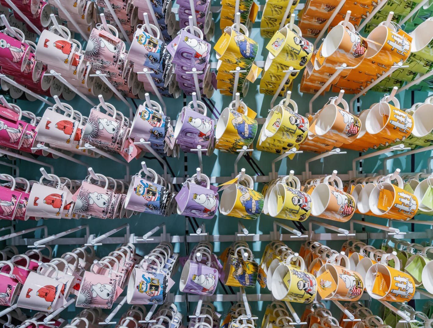 Reol med varekroker hvor det henger mange Mummikopper med forskjellige motiver.