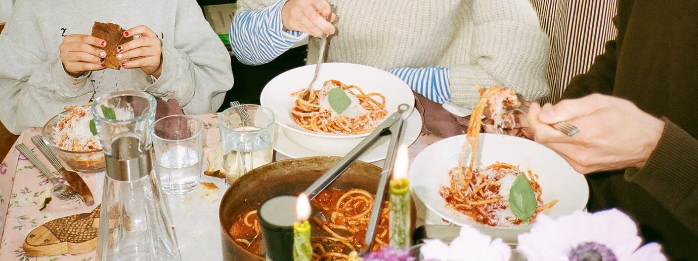 En familie sitter ved et bord og spiser spaghetti. Bordet er dekket med Grand Cru-serviset fra Rosendahl.